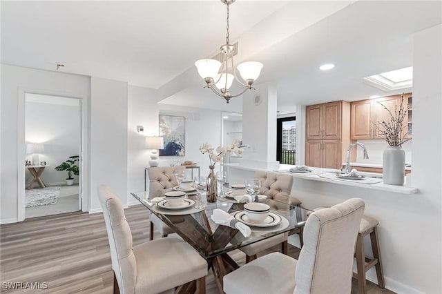 dining area featuring recessed lighting, a skylight, light wood finished floors, a notable chandelier, and baseboards