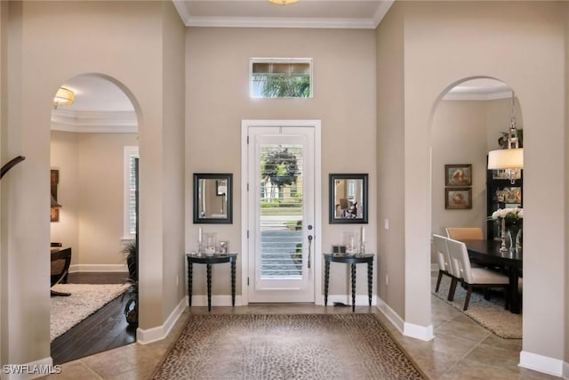 foyer with light tile patterned floors, a towering ceiling, and crown molding