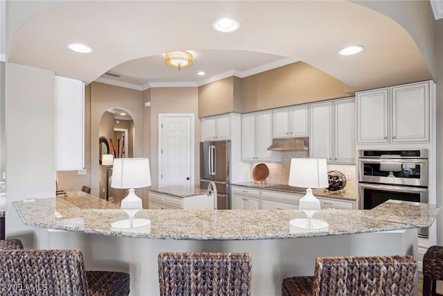 kitchen featuring kitchen peninsula, white cabinetry, light stone counters, and stainless steel appliances