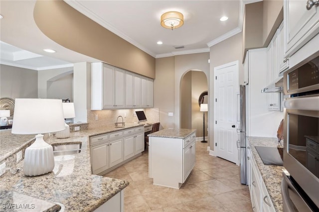 kitchen with a center island, white cabinets, crown molding, decorative backsplash, and light stone countertops