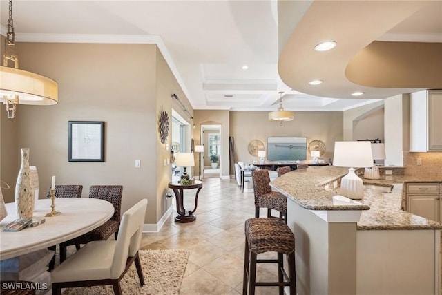 kitchen featuring backsplash, light stone counters, pendant lighting, a breakfast bar area, and light tile patterned flooring