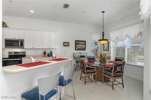 kitchen with decorative light fixtures, light tile patterned floors, stainless steel appliances, and white cabinetry