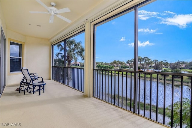 sunroom / solarium with ceiling fan and a water view