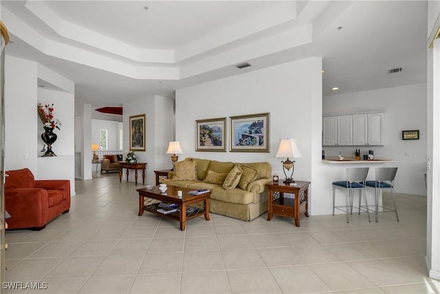 living room featuring a raised ceiling and light tile patterned floors