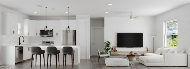 kitchen with sink, a center island, hanging light fixtures, white cabinets, and appliances with stainless steel finishes