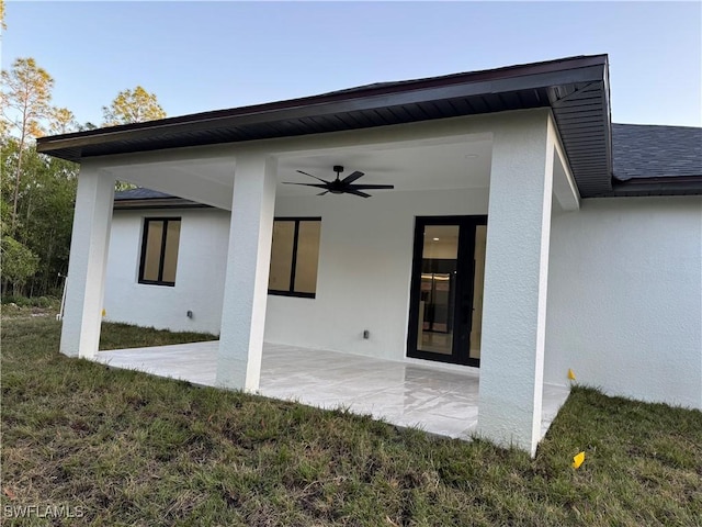 rear view of house with ceiling fan, a yard, and a patio