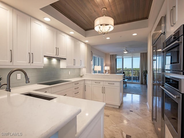 kitchen with wooden ceiling, black electric stovetop, white cabinets, a raised ceiling, and kitchen peninsula