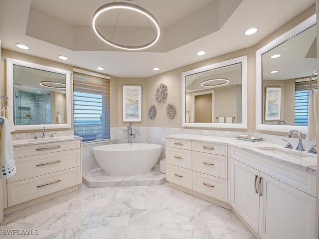 bathroom featuring vanity, a tub to relax in, a raised ceiling, and tile walls