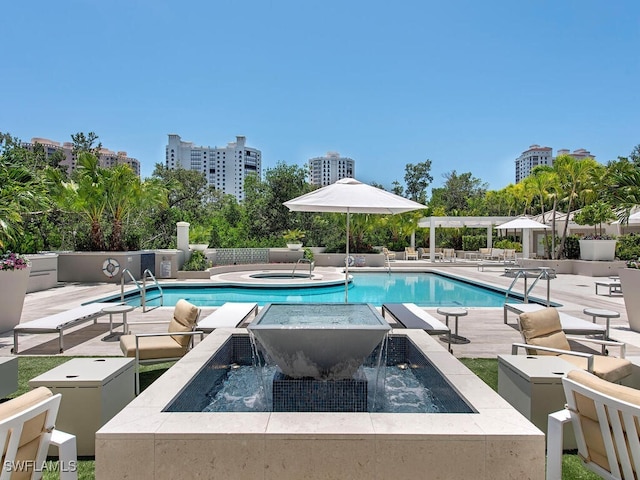 view of pool featuring pool water feature, a patio, and a hot tub