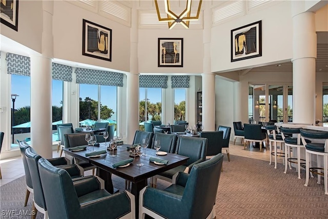 dining space featuring a healthy amount of sunlight, tile patterned floors, decorative columns, and a high ceiling