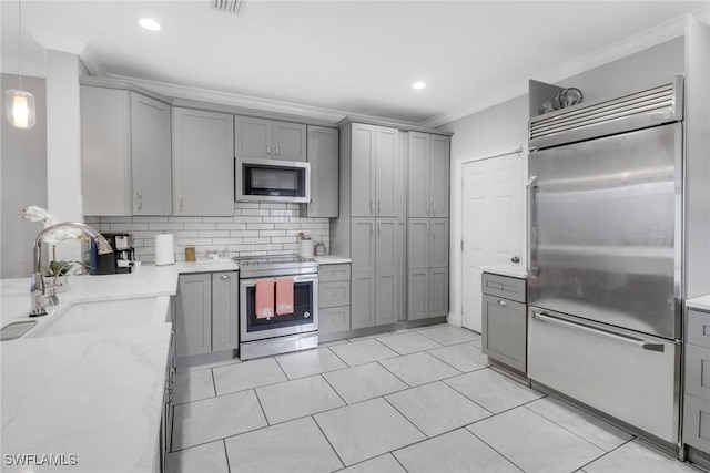 kitchen with built in appliances, hanging light fixtures, gray cabinets, crown molding, and a sink