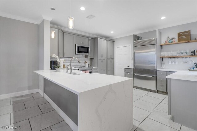 kitchen with gray cabinetry, sink, built in appliances, decorative light fixtures, and kitchen peninsula