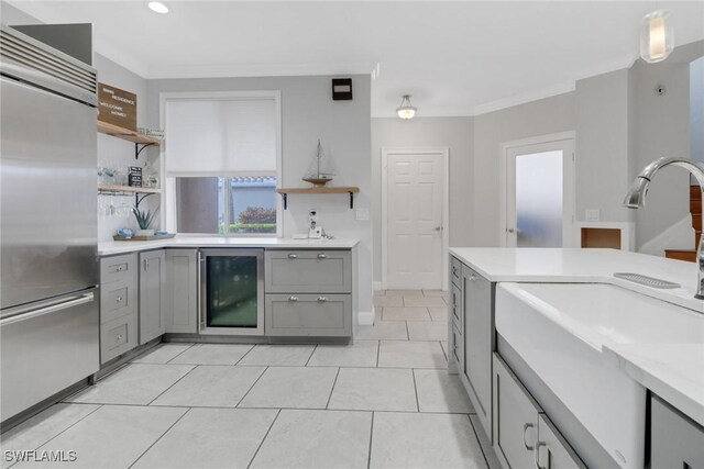 kitchen featuring gray cabinetry, crown molding, pendant lighting, wine cooler, and built in fridge