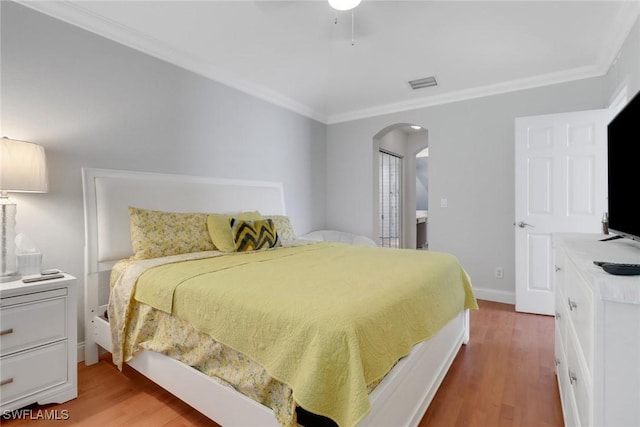 bedroom with visible vents, crown molding, arched walkways, and wood finished floors