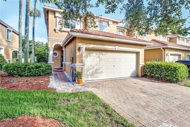 view of front of property with decorative driveway, a tiled roof, an attached garage, and stucco siding