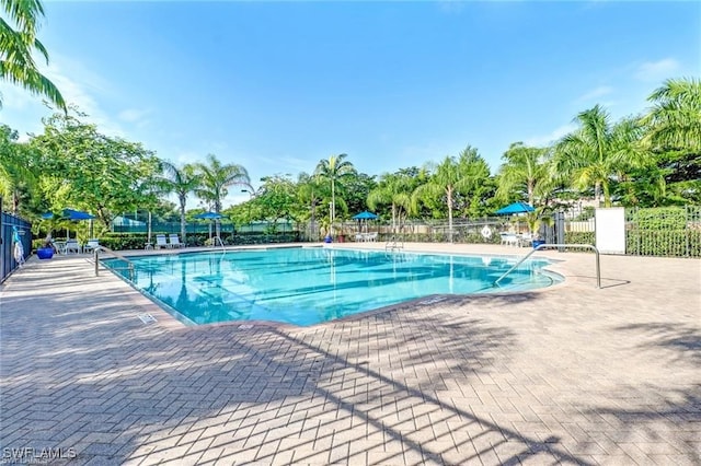 community pool with a patio area and fence