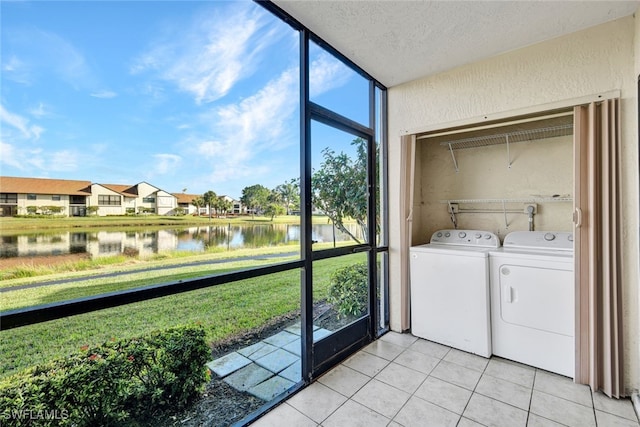 laundry area with separate washer and dryer, a textured ceiling, a water view, and light tile patterned flooring