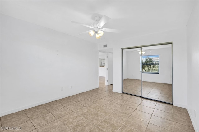 unfurnished bedroom with light tile patterned floors, a closet, and ceiling fan