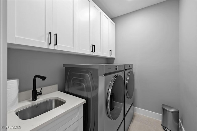 laundry room featuring washer and clothes dryer, cabinets, light tile patterned floors, and sink