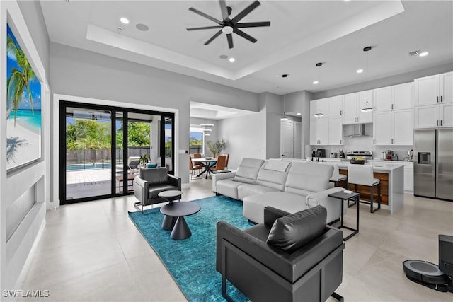 living room with a raised ceiling and ceiling fan