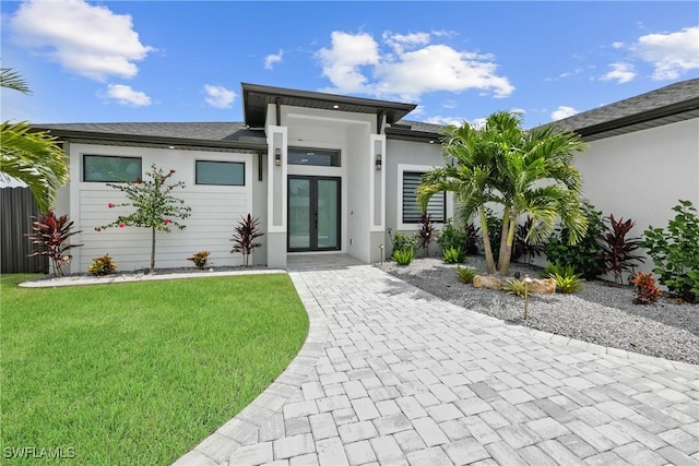 rear view of property featuring french doors and a lawn