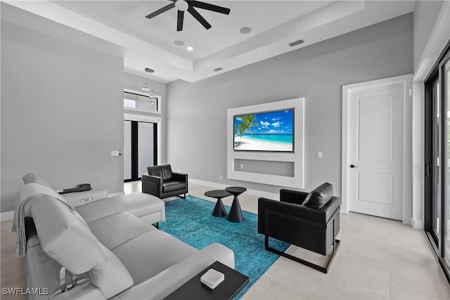 living room featuring a raised ceiling and ceiling fan