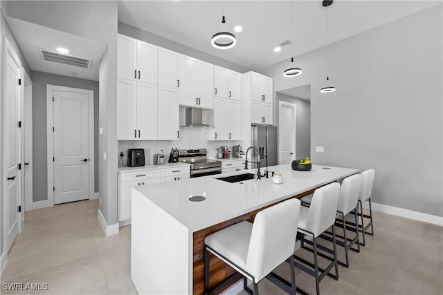 kitchen with sink, decorative light fixtures, a breakfast bar, a center island with sink, and appliances with stainless steel finishes