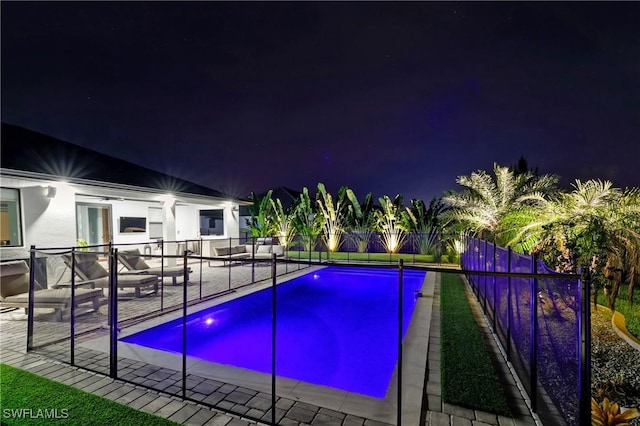 pool at night featuring a patio area