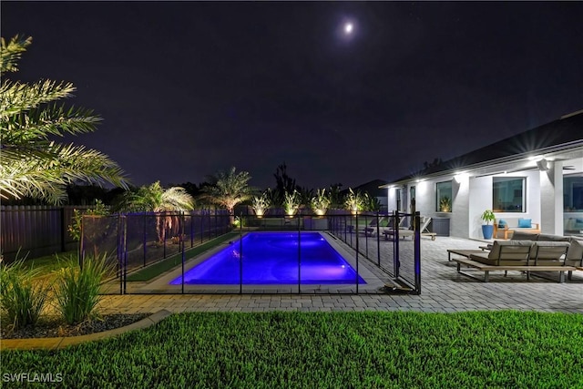 pool at night with a patio area and an outdoor hangout area