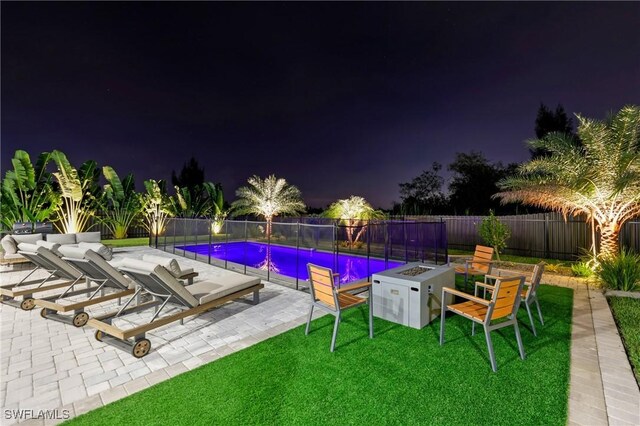 pool at twilight featuring a fire pit, a patio, and a lawn