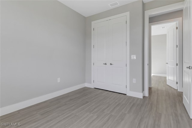 unfurnished bedroom with light wood-type flooring and a closet