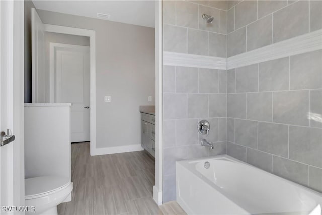 full bathroom featuring vanity, wood-type flooring, tiled shower / bath combo, and toilet