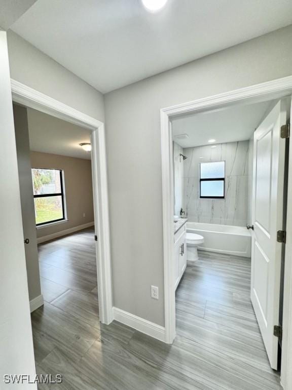 full bathroom featuring hardwood / wood-style floors, vanity, toilet, and tiled shower / bath