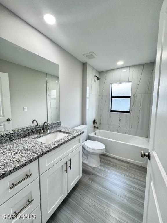 full bathroom featuring wood-type flooring, vanity, toilet, and tiled shower / bath