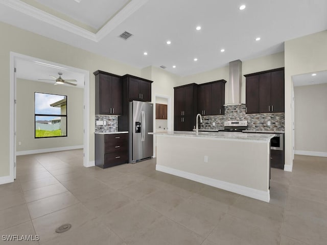 kitchen with appliances with stainless steel finishes, tasteful backsplash, wall chimney exhaust hood, dark brown cabinets, and ceiling fan