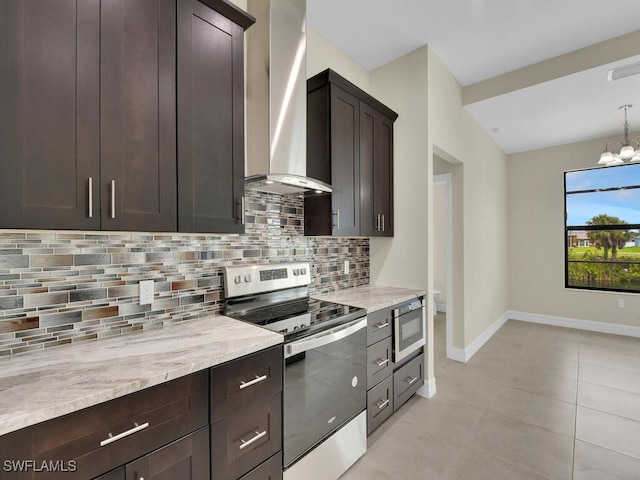 kitchen featuring appliances with stainless steel finishes, tasteful backsplash, wall chimney exhaust hood, dark brown cabinets, and a notable chandelier