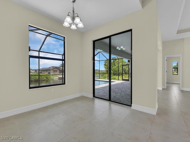 tiled empty room with a wealth of natural light and an inviting chandelier