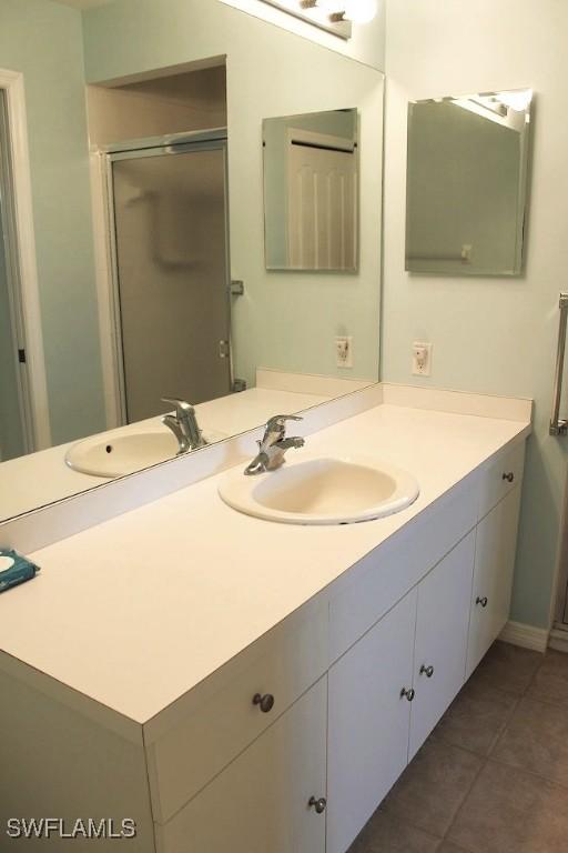 bathroom featuring tile patterned floors, vanity, and a shower with door