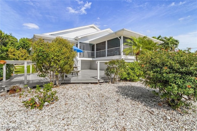 rear view of house with a sunroom and a wooden deck