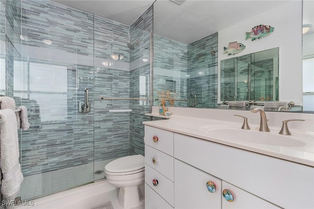 bathroom with vanity, toilet, and a shower with door