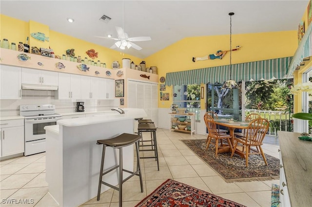 kitchen featuring light tile patterned floors, vaulted ceiling, white cabinetry, and white electric stove