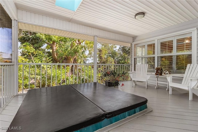 unfurnished sunroom featuring wood ceiling and a skylight