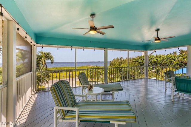 sunroom / solarium with ceiling fan and a water view