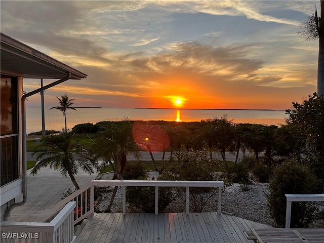 deck at dusk featuring a water view