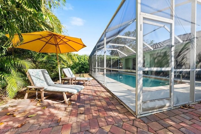 view of pool with glass enclosure and a patio