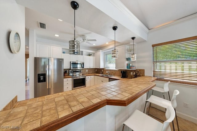 kitchen with white cabinetry, sink, stainless steel appliances, kitchen peninsula, and a breakfast bar area