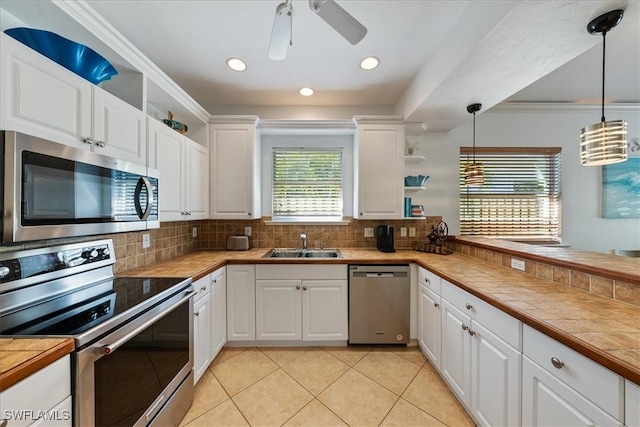 kitchen featuring hanging light fixtures, stainless steel appliances, tasteful backsplash, tile countertops, and white cabinets