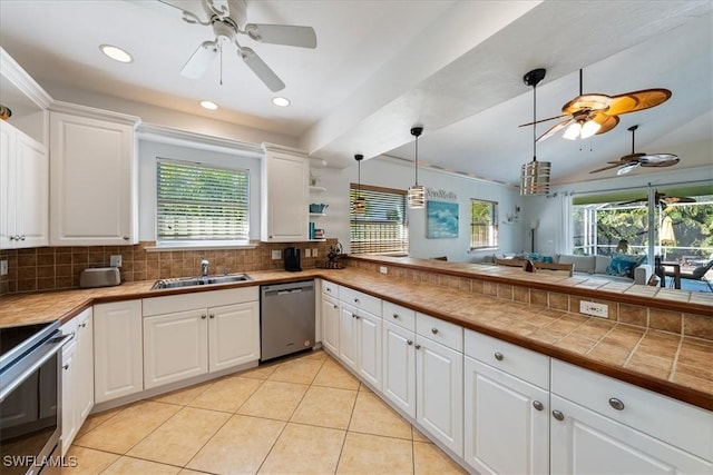 kitchen featuring white cabinets, tile countertops, stainless steel dishwasher, and sink