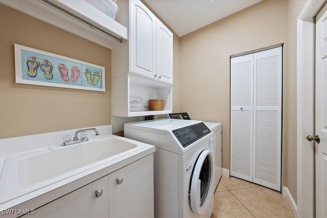 clothes washing area with cabinets, light tile patterned floors, sink, and washing machine and clothes dryer