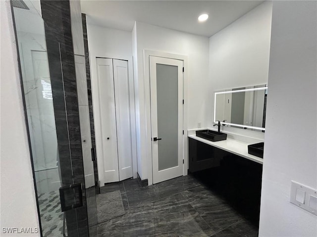 bathroom with a tile shower and vanity